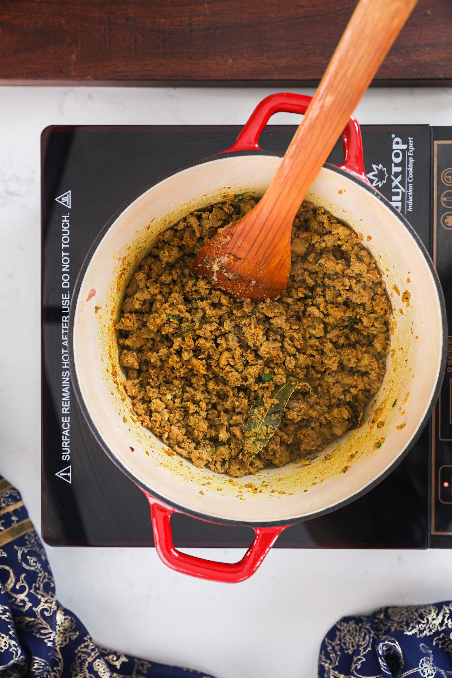 A pot of minced chicken topped on a mobile cooktop.