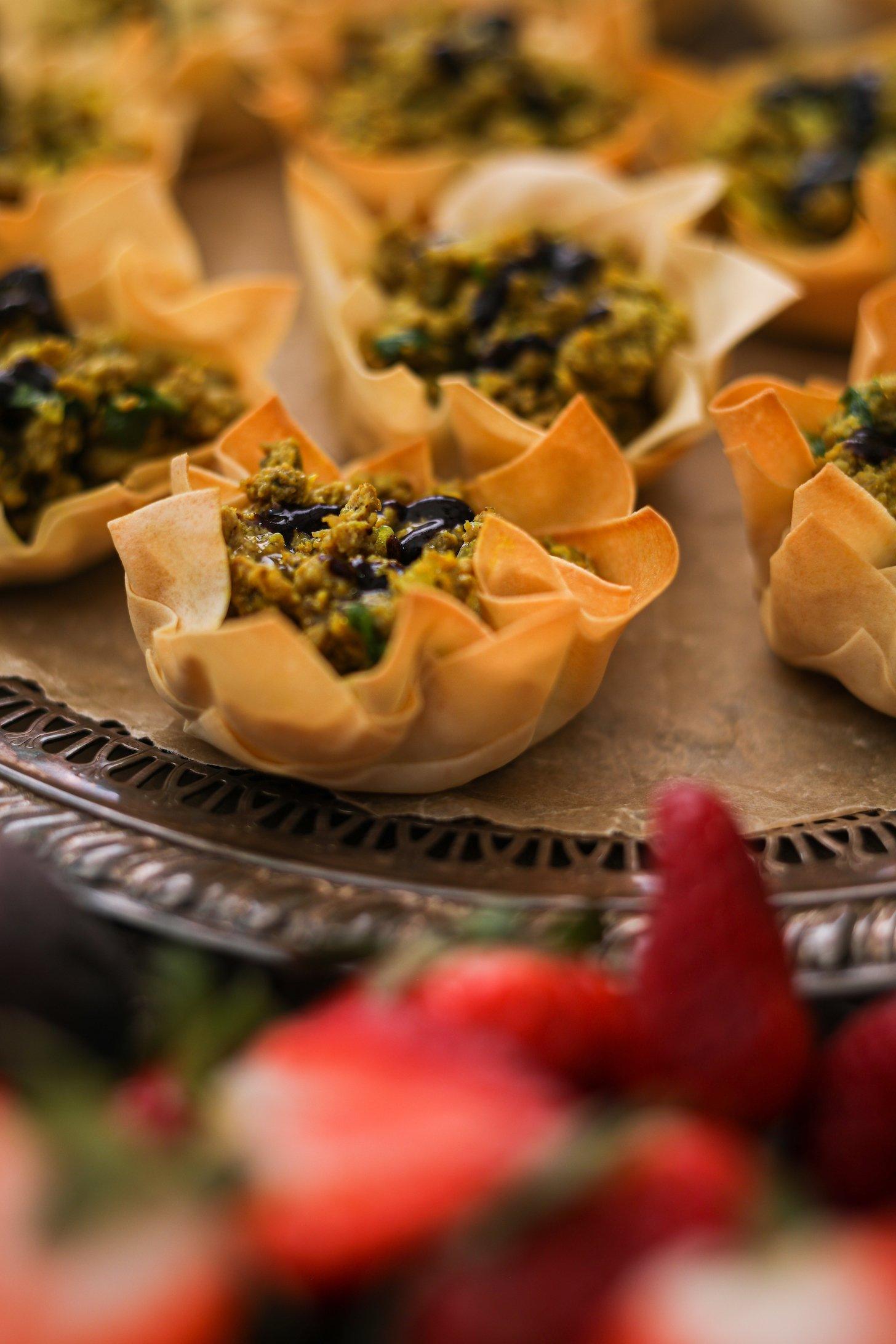 Close up of a pastry shell filled with cooked chicken and topped with a dark dressing.