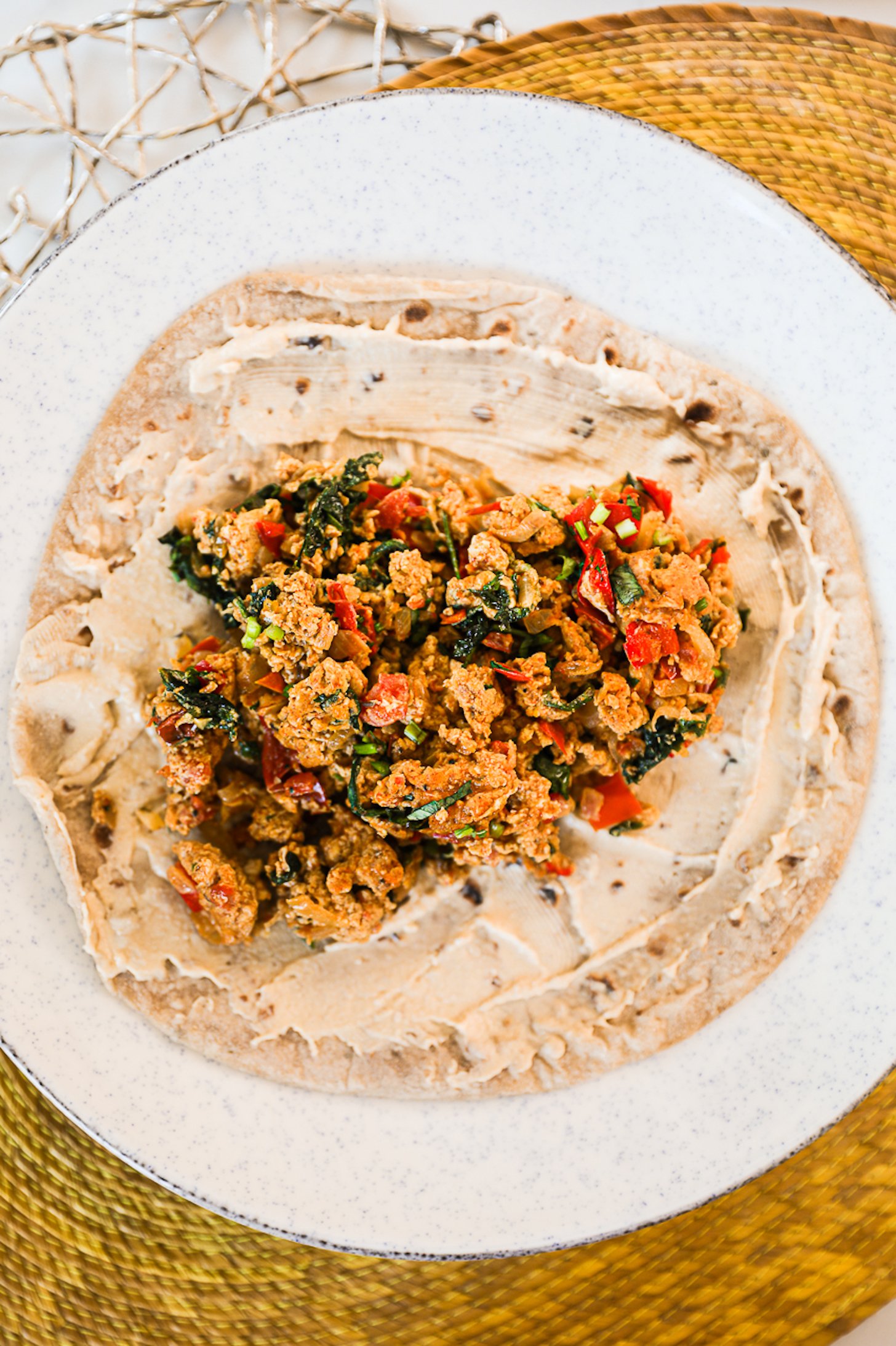 Overhead view of roti coated with hummus and a pile of egg bhurji.