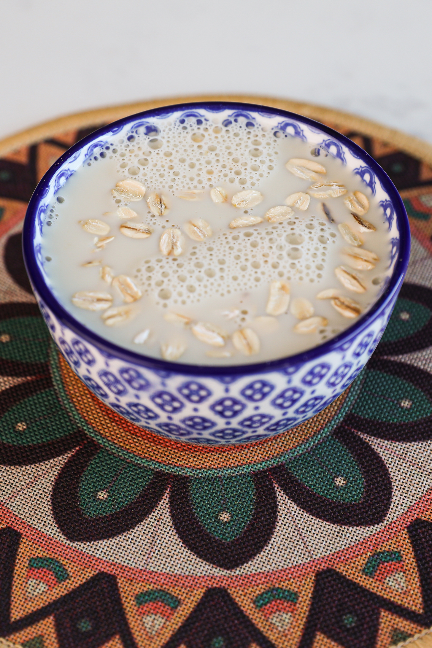 A ramekin of oats soaked in milk placed on a floral mat.