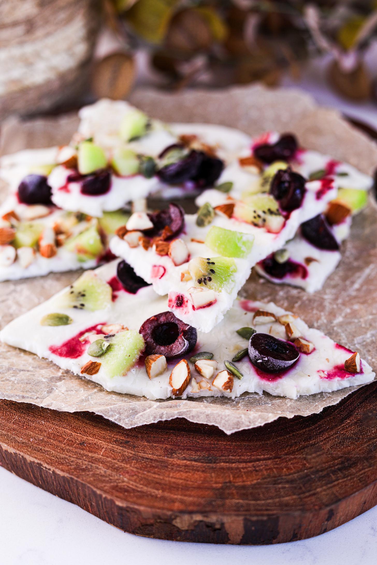 Perspective image featuring stacked frozen yogurt bark pieces, topped with fruits and nuts.