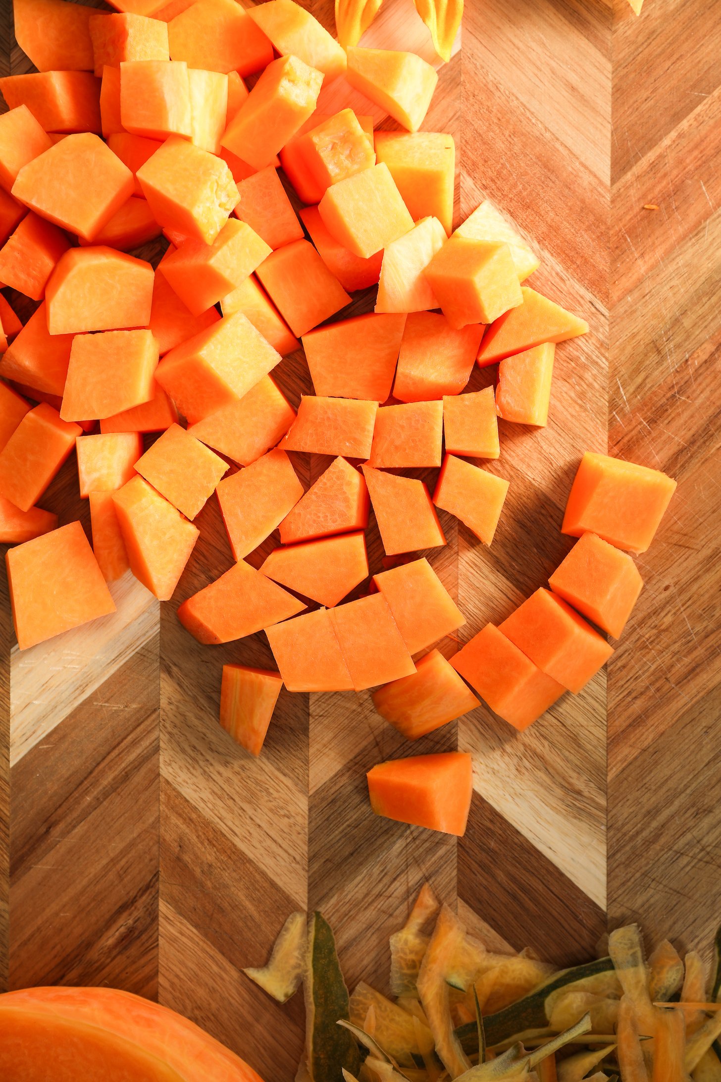 Chopped pumpkin pieces spread out on a wooden board.