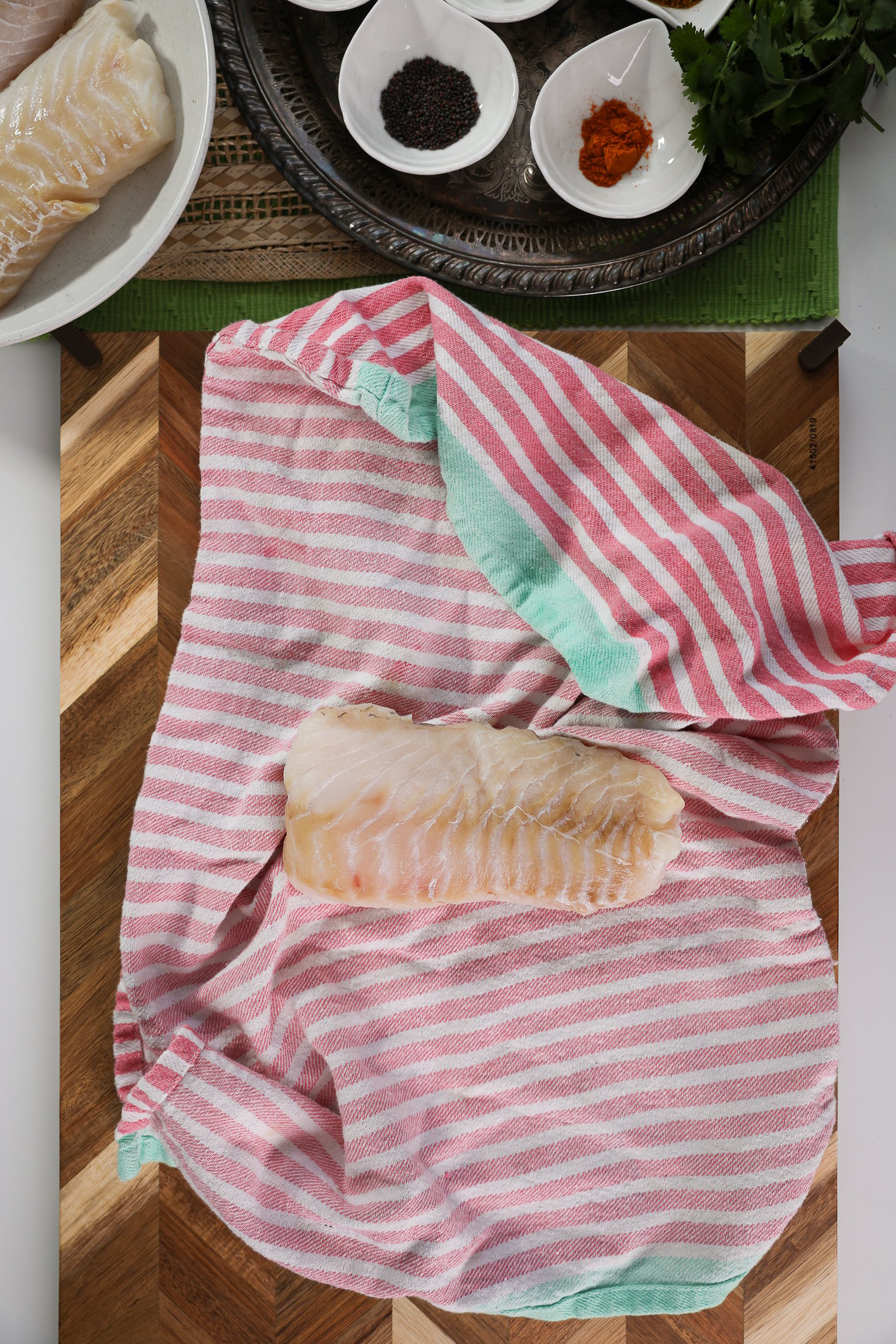 A large fish fillet placed on a kitchen towel on a wooden board.