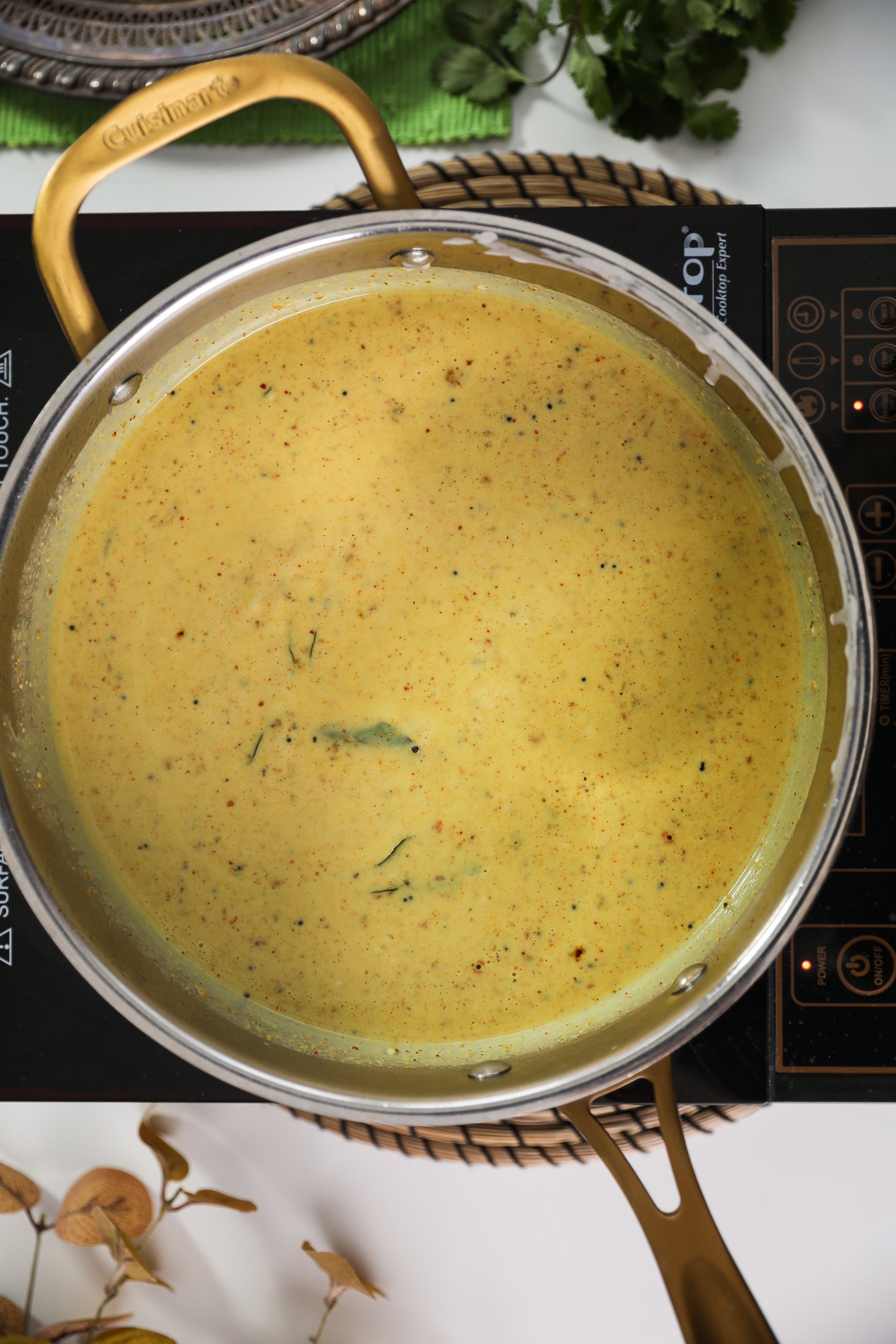Pan of yellow grainy sauce on a mobile cooktop.