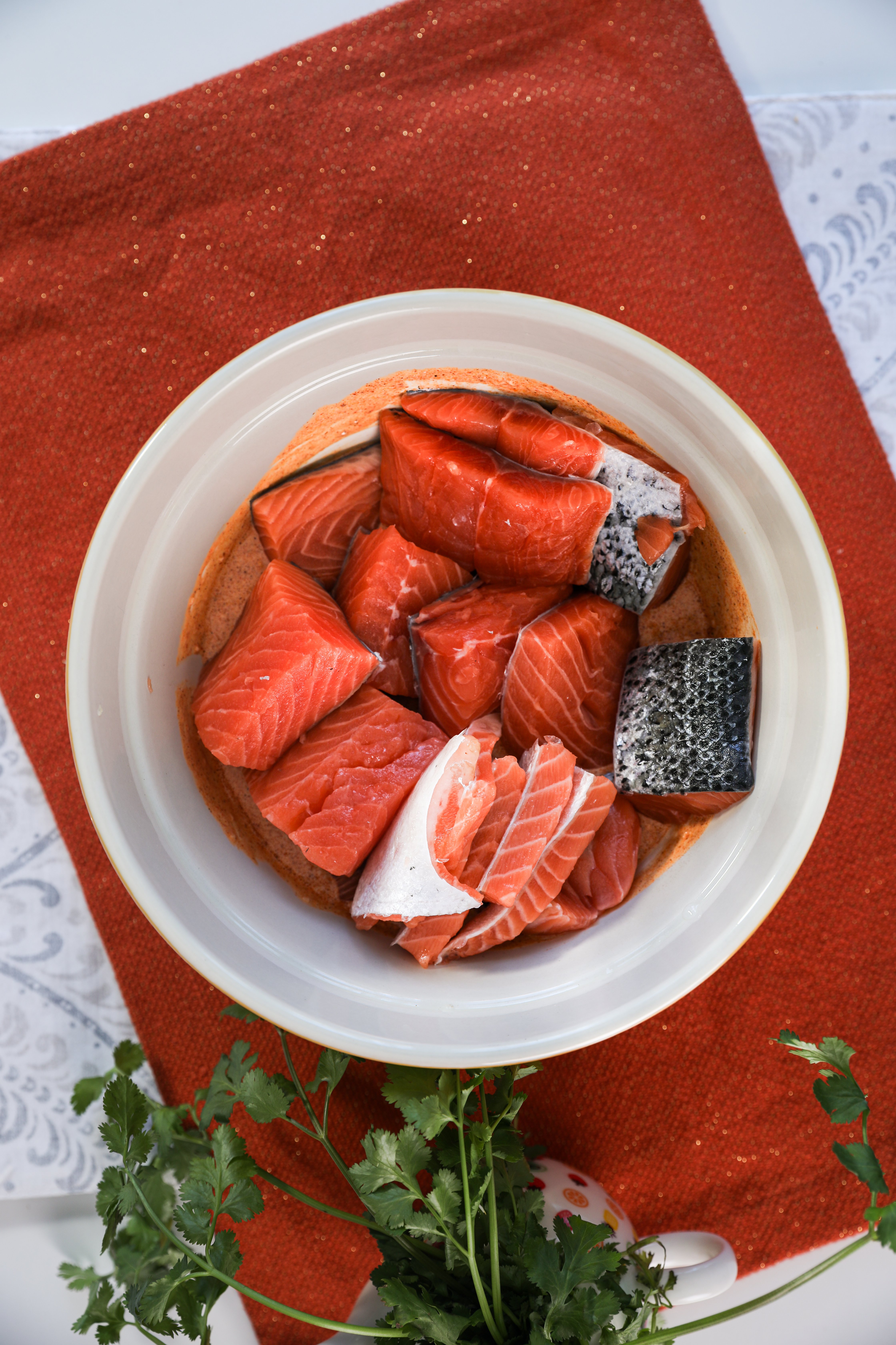 A bowl containing fresh salmon pieces sits on an orange mat.
