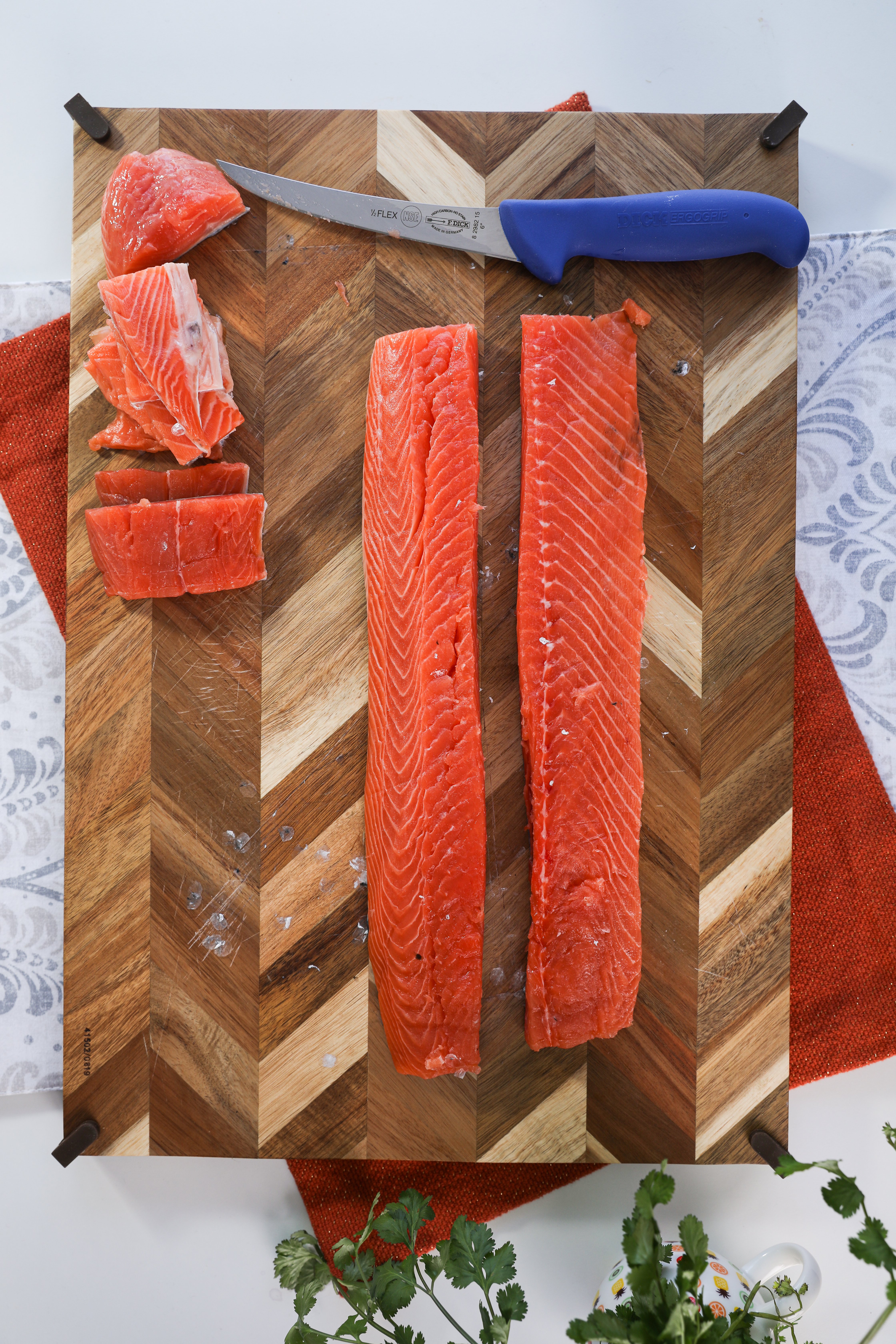 Fresh salmon fillet sliced into two strips, neatly presented on a wooden board alongside a knife.