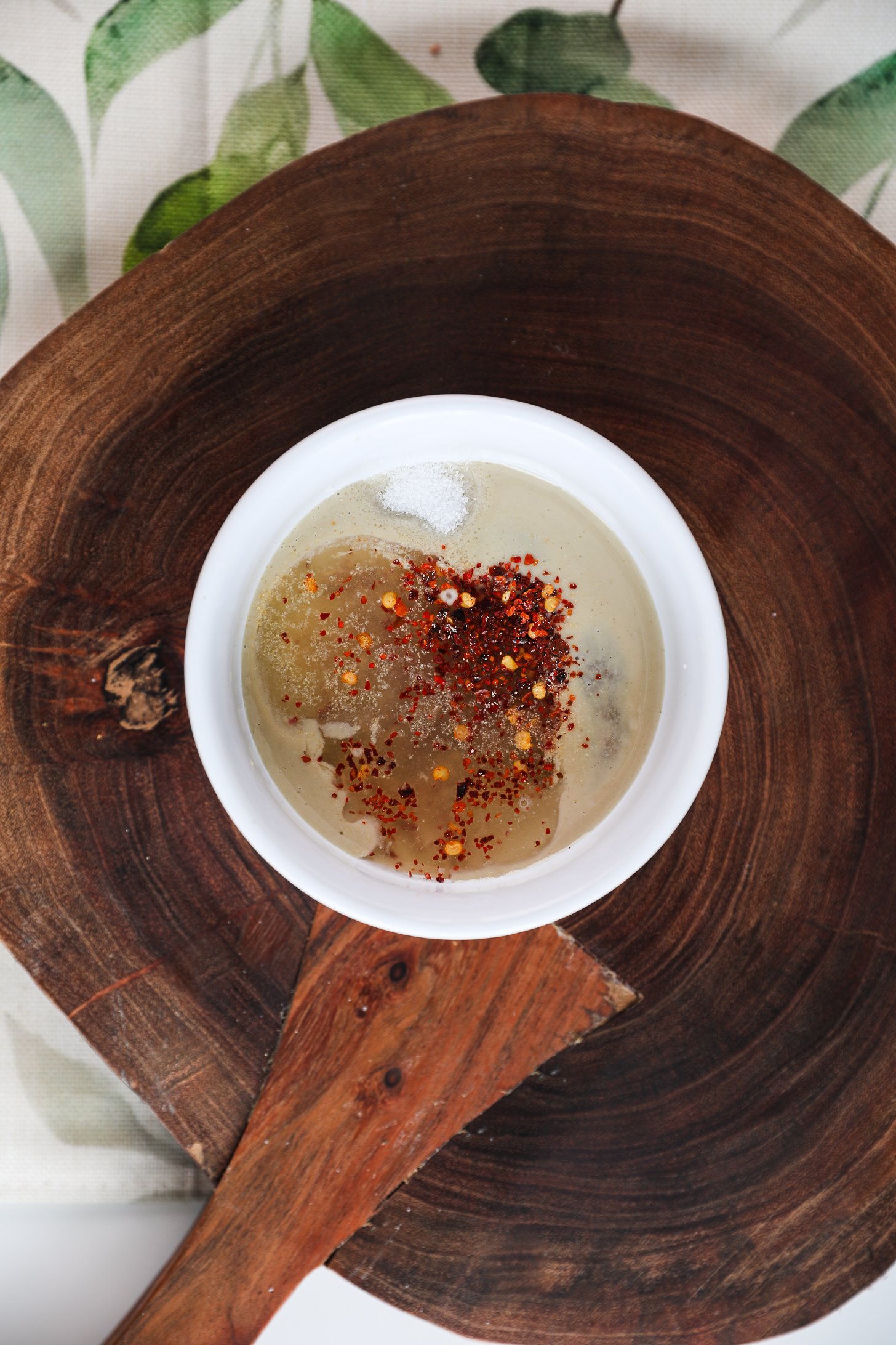 Top view of a bowl with tahini, lemon, salt and chilli flakes.