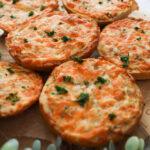 Perspective image of round cheesy garlic breads with a plant in the foreground.