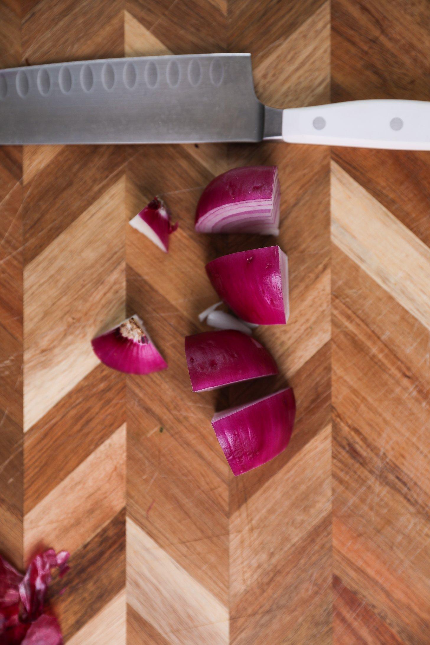 A half onion, precisely sliced in quarters, with a knife nearby.