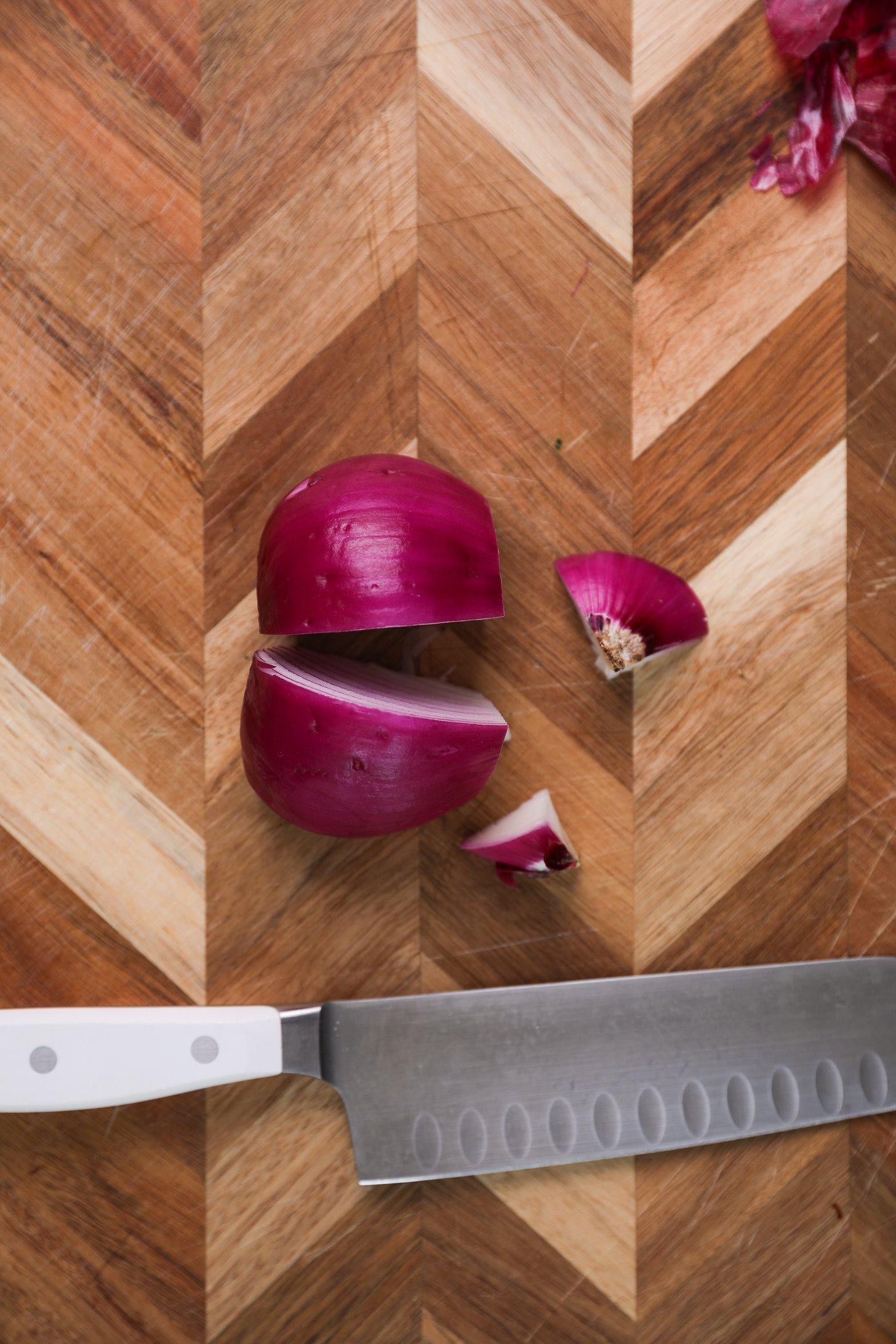 A half onion, precisely sliced in half, with a knife nearby.