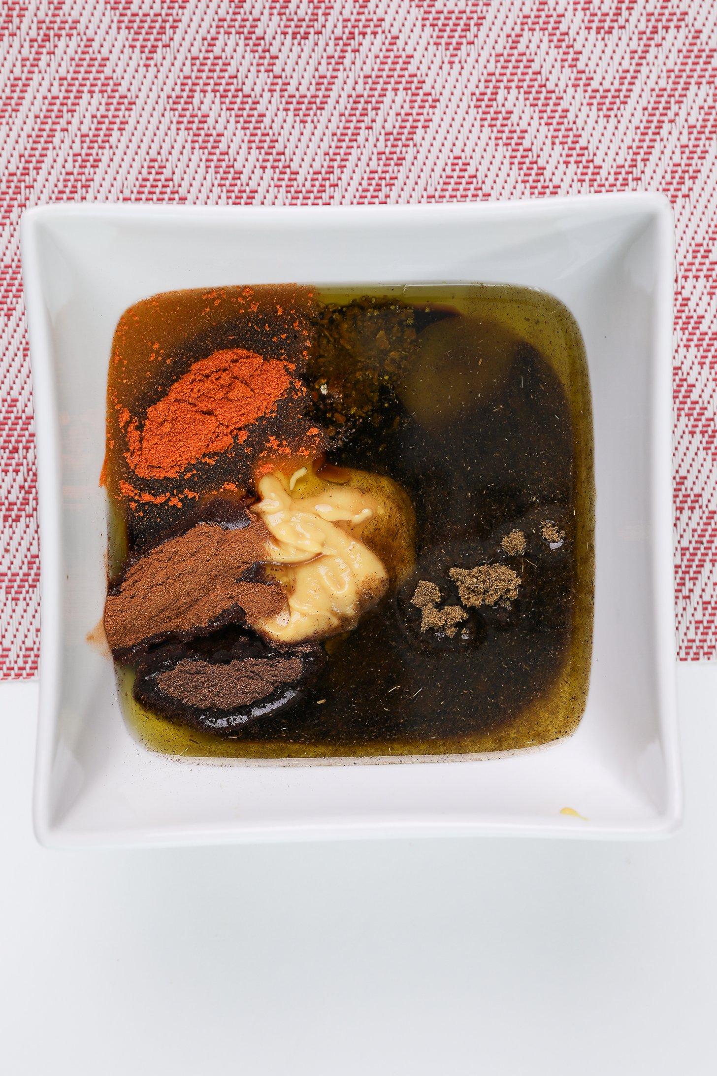 A bowl of oil, spices, mustard and soy sauce - ready to be mixed.