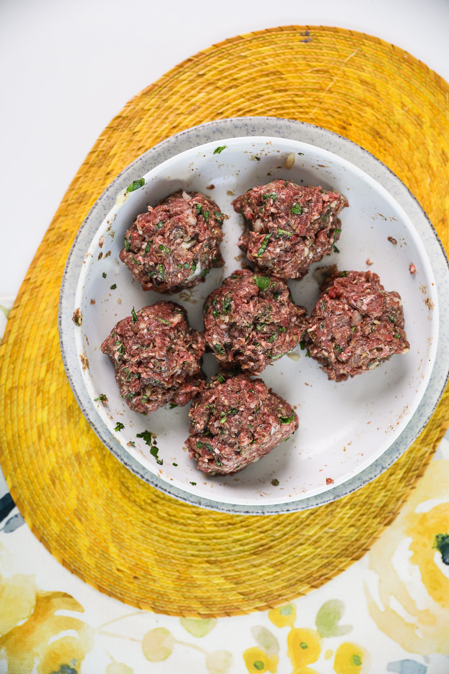 Six balls of raw mince beef in a bowl.