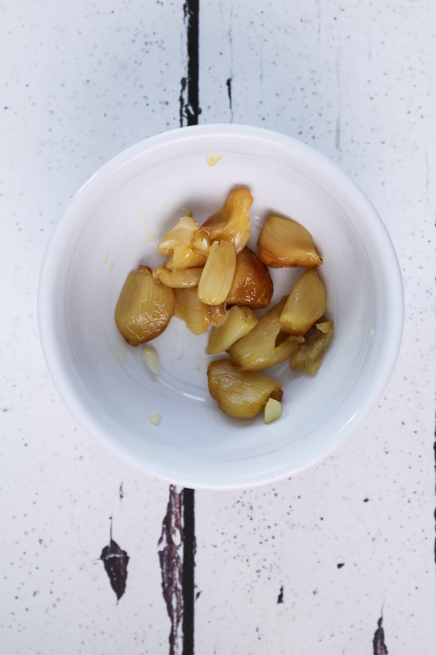 Cloves of roasted garlic in a small white bowl.