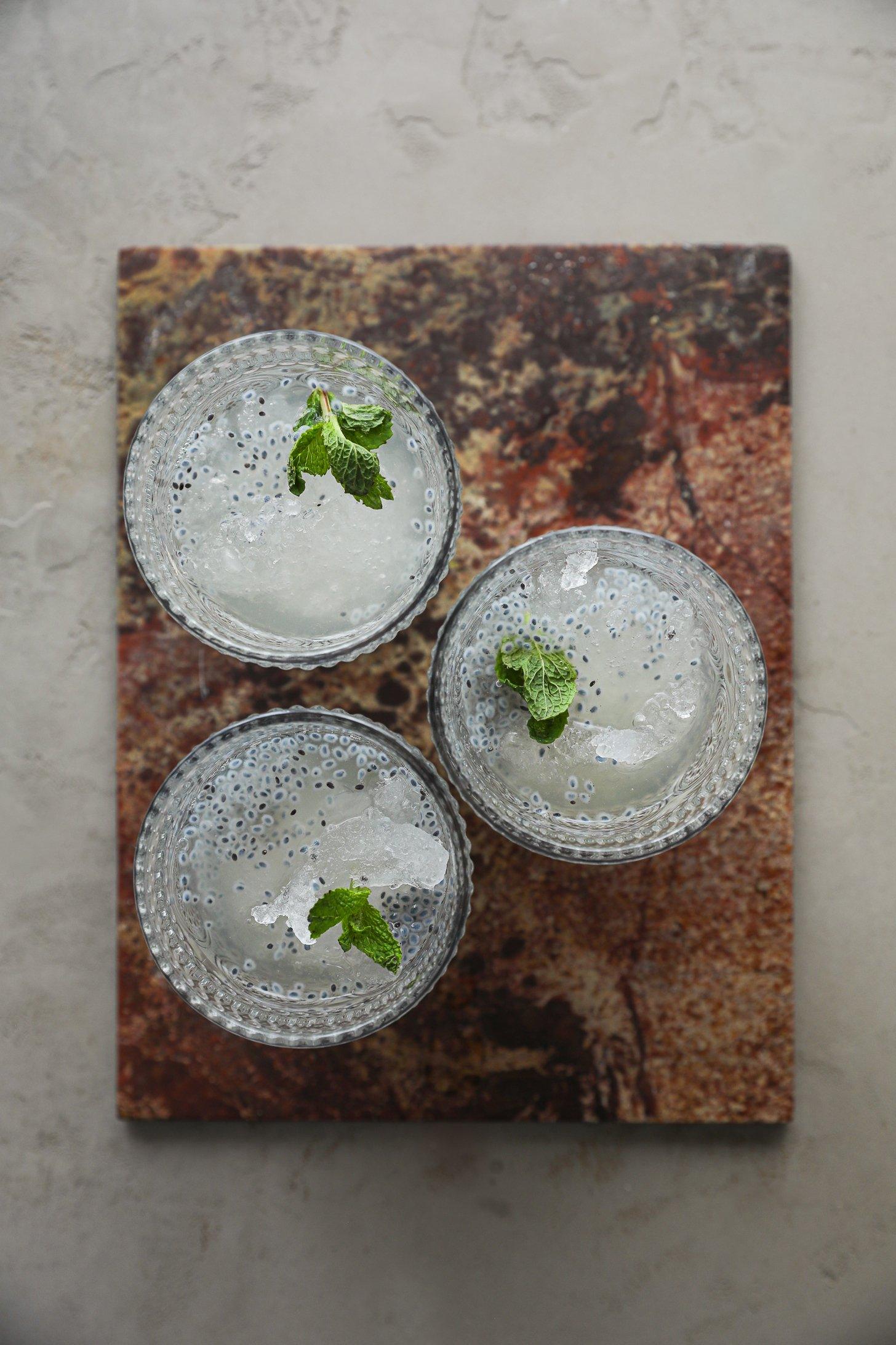 An image of 3 glasses filled with ice, water and basil seeds with sprigs of mint in each.