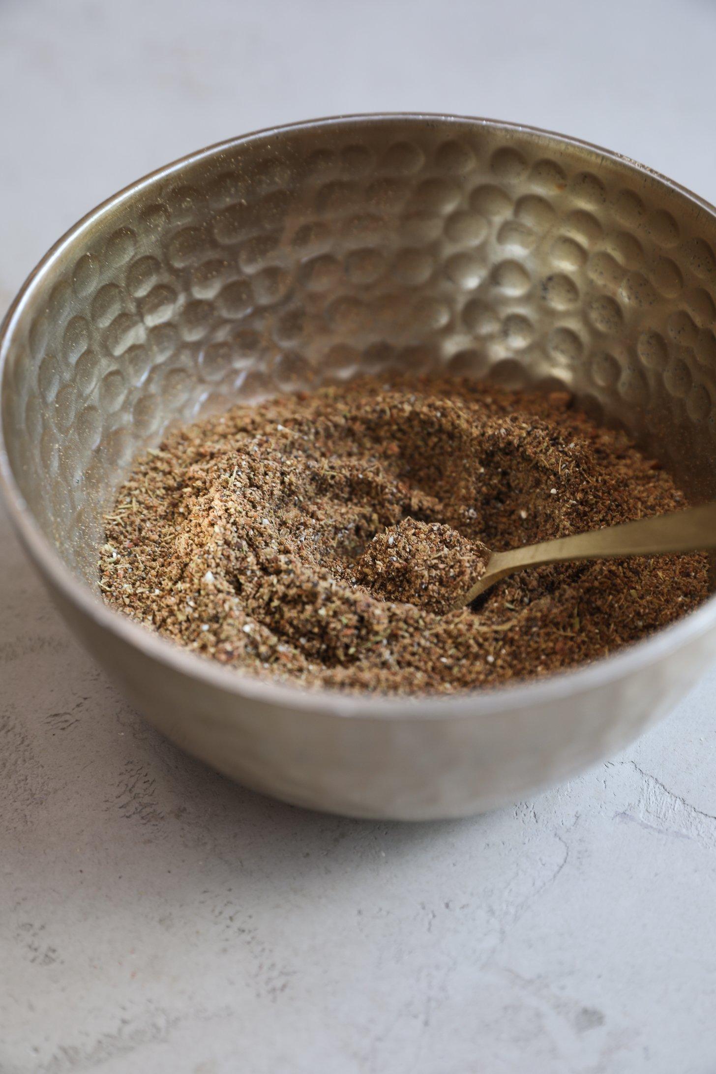 A bowl of freshly ground chai masala with a warm, textured appearance.