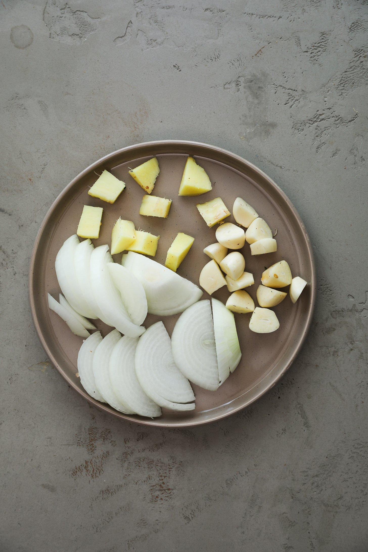 Sliced onion, garlic cloves, and fresh ginger.