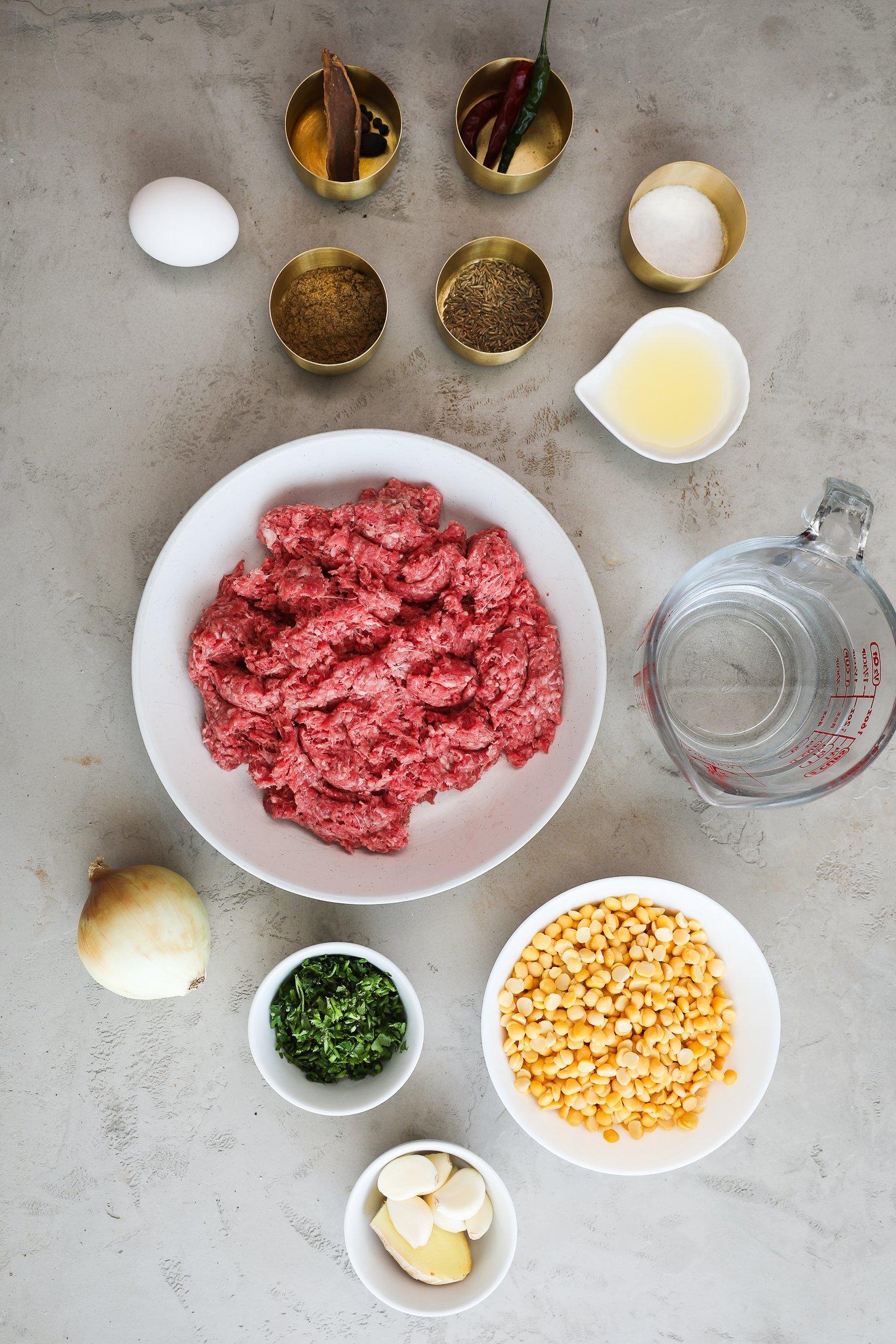 Raw ingredients for making beef kebabs including ground beef, chana dal, and spices.