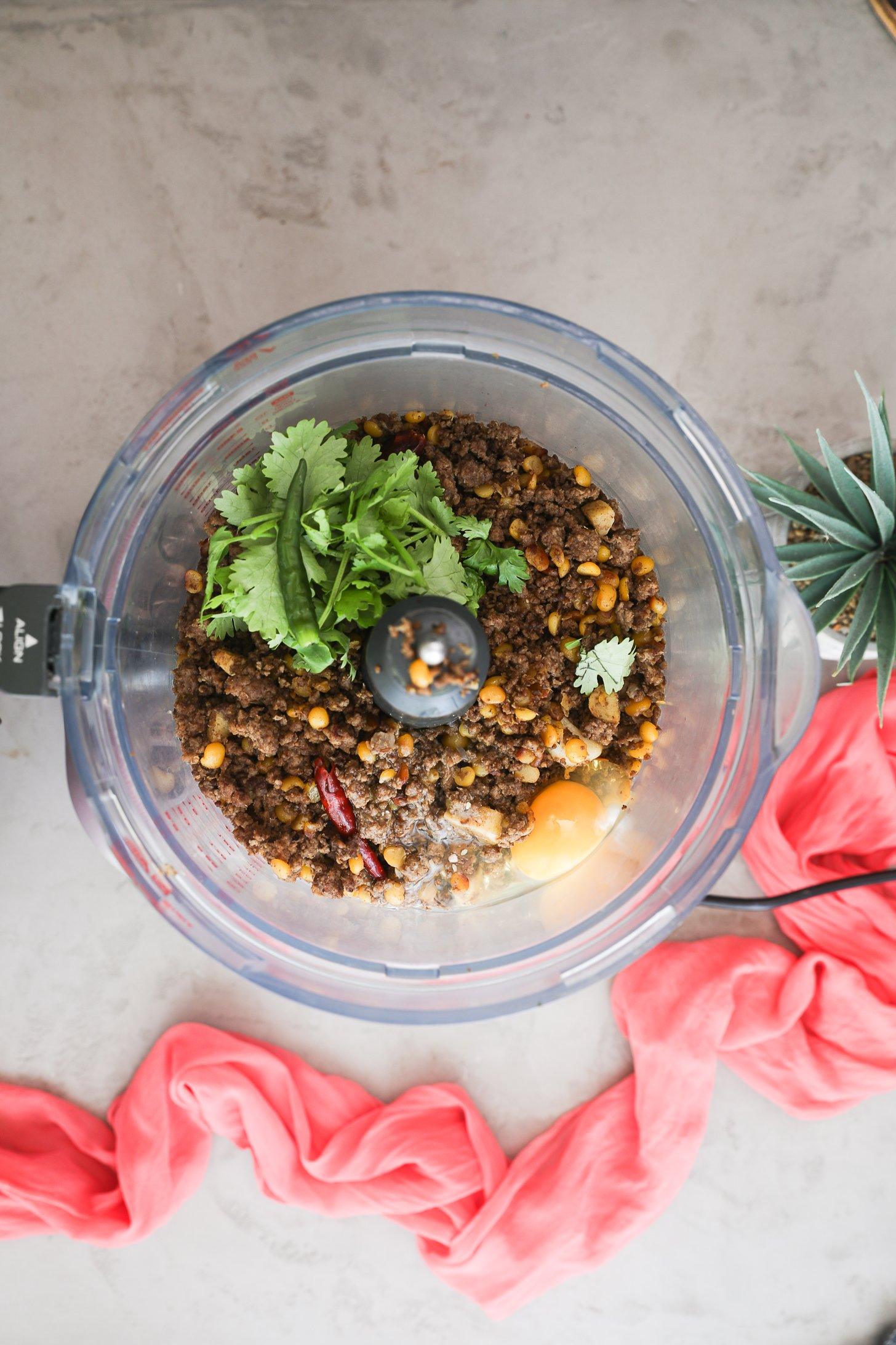 Cooked beef, dal, herbs, chilli, and egg in a food processor.