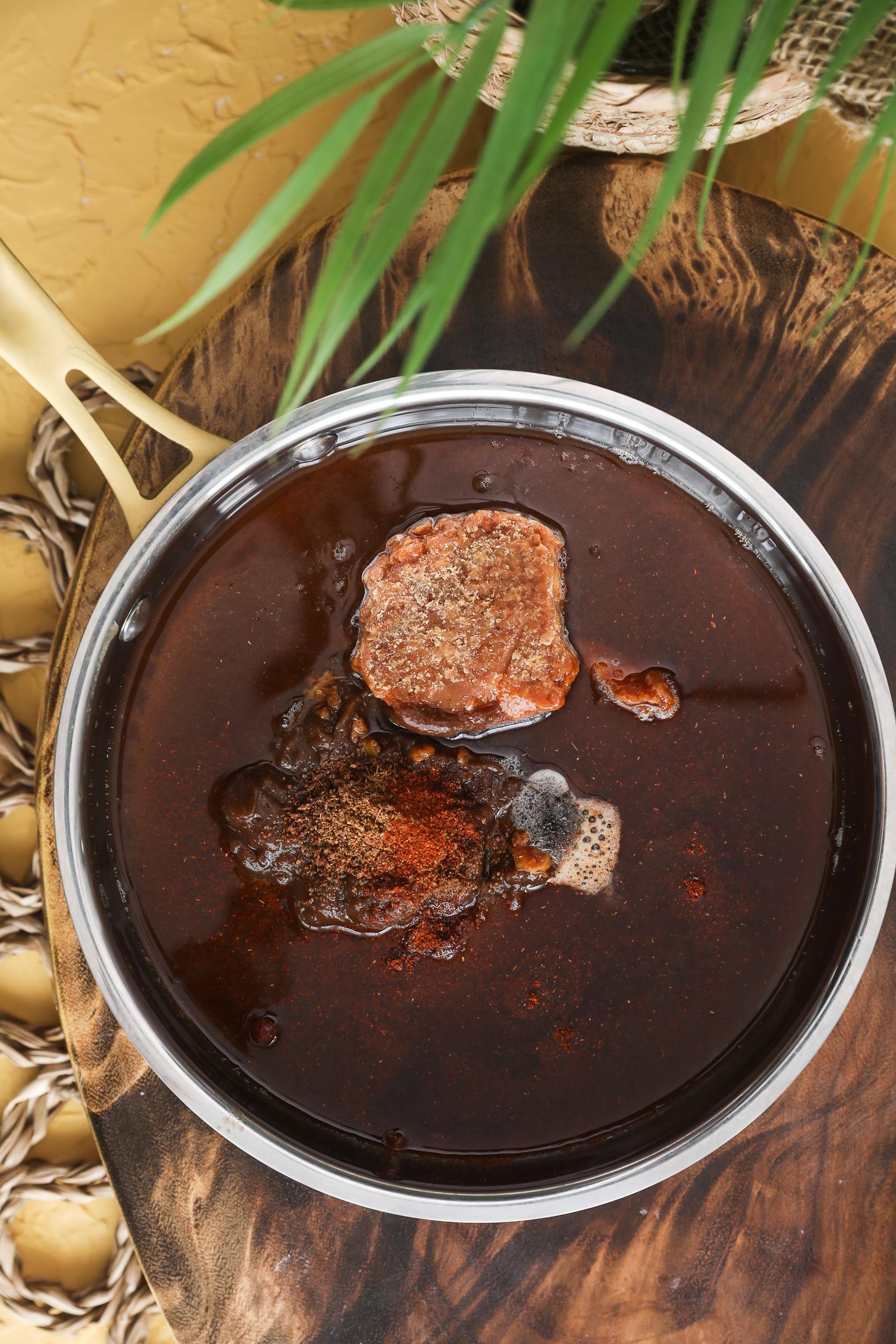 Tamarind pulp in saucepan with jaggery, cumin, and chili powder before simmering.