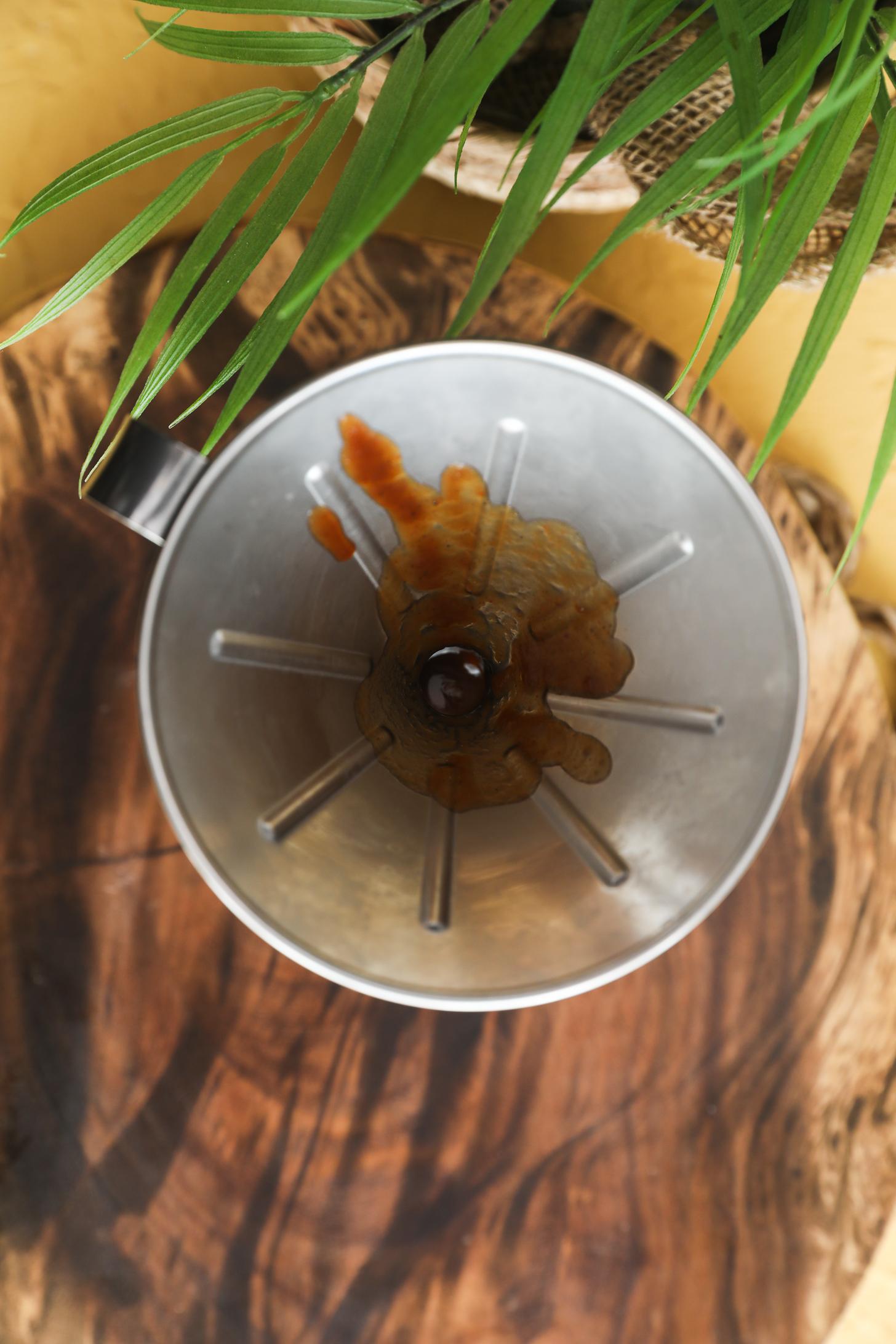 Pouring tamarind chutney through funnel into glass jar.
